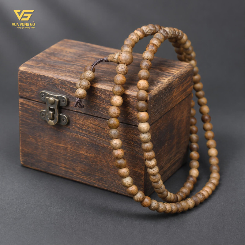Vòng tay Trầm Hương 108 hạt làm từ trầm tốc vườn, nổi bật với sắc gỗ vàng nâu và những đường vân dầu